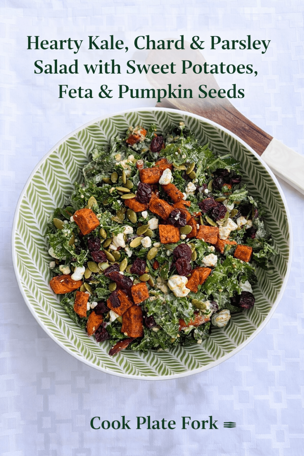 Overhead view of hearty kale, chard and parsley salad with roasted sweet potatoes, feta cheese, pumpkin seeds and dried cranberries.